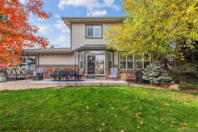 back of house featuring brick siding, a patio area, and a yard