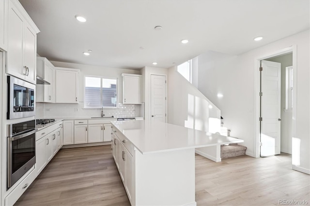 kitchen with white cabinets, a center island, sink, and stainless steel appliances