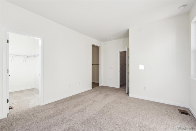 unfurnished bedroom with light carpet, a walk in closet, and a closet