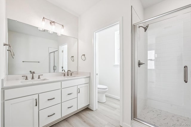 bathroom featuring vanity, wood-type flooring, a shower with shower door, and toilet