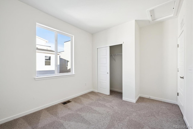 unfurnished bedroom with light colored carpet and a closet