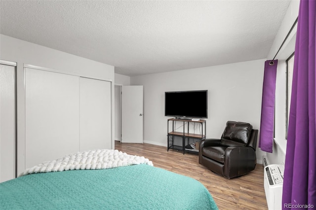 bedroom featuring baseboards, a textured ceiling, and wood finished floors