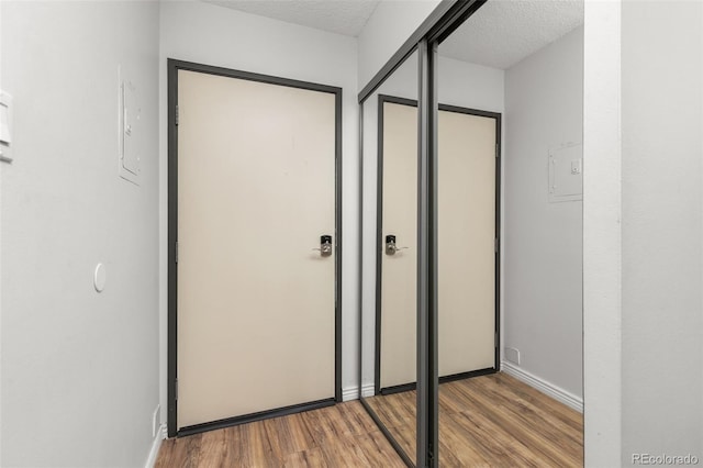 interior space featuring baseboards, a textured ceiling, wood finished floors, and a closet
