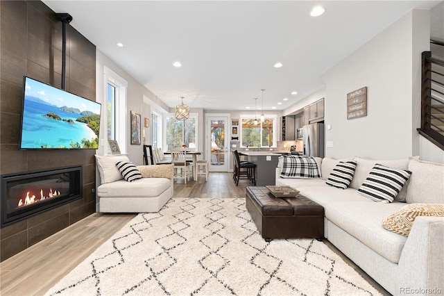 living room with light hardwood / wood-style flooring, a tiled fireplace, and a chandelier