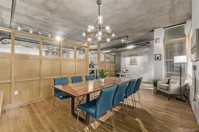 dining area with light hardwood / wood-style floors and an inviting chandelier