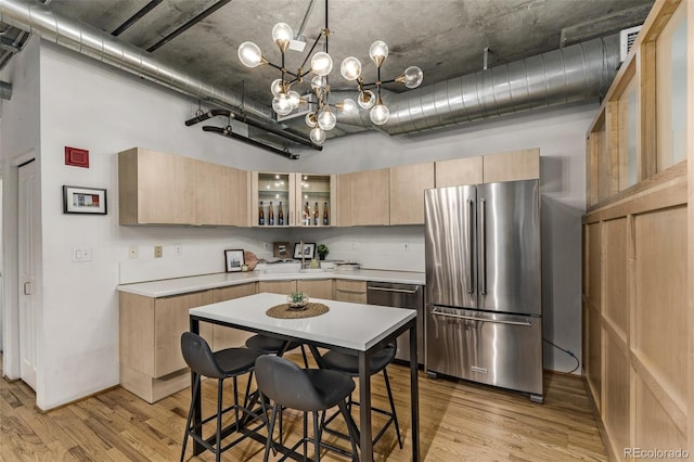 kitchen with an inviting chandelier, sink, light brown cabinetry, light hardwood / wood-style floors, and stainless steel appliances