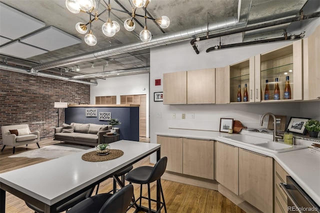 kitchen featuring brick wall, light brown cabinetry, light hardwood / wood-style floors, and sink