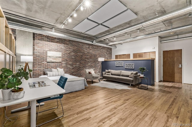 living room with hardwood / wood-style floors, brick wall, and track lighting