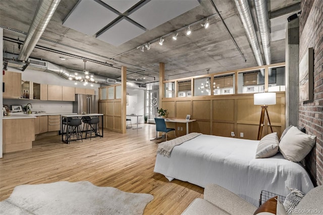 bedroom with sink, light hardwood / wood-style flooring, high end fridge, and brick wall