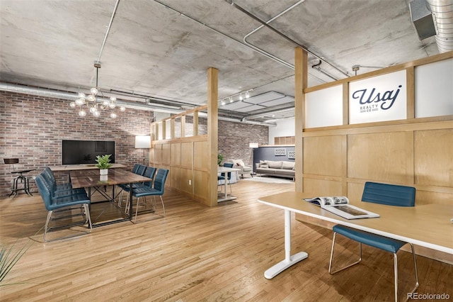 dining room with brick wall, a chandelier, and hardwood / wood-style floors