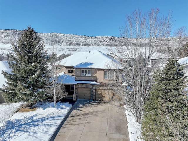 view of front of property with an attached garage, a mountain view, concrete driveway, and stucco siding