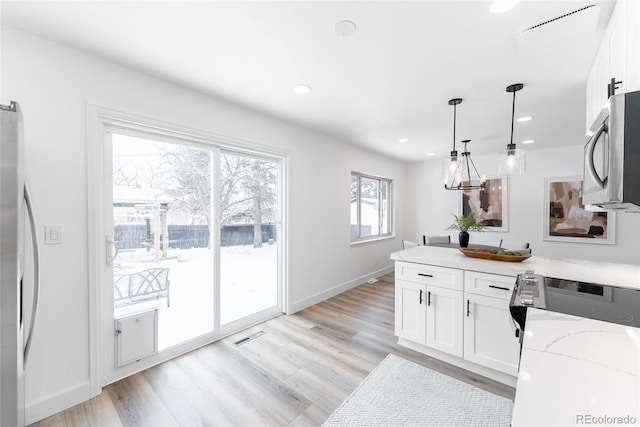 kitchen with white cabinetry, pendant lighting, stainless steel appliances, and light stone counters