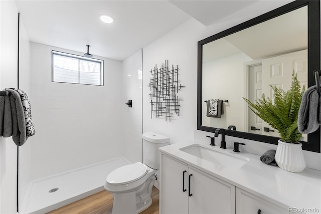 bathroom with a tile shower, toilet, vanity, and hardwood / wood-style flooring