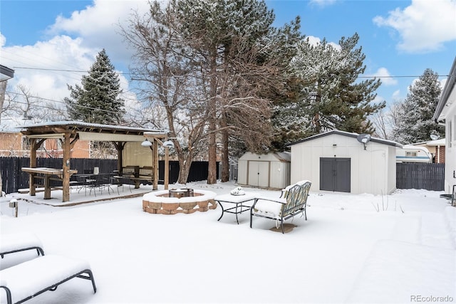 snowy yard featuring a storage unit and an outdoor fire pit