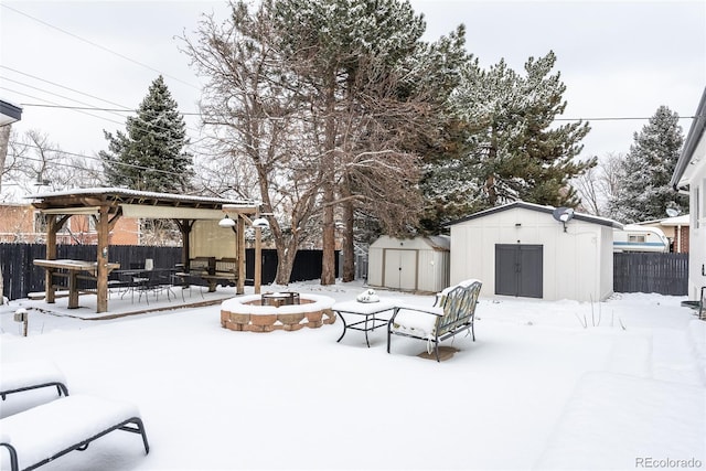 yard covered in snow with a storage unit and an outdoor fire pit