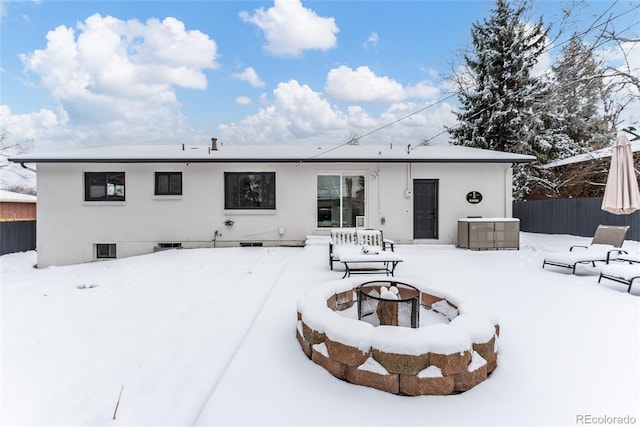 snow covered rear of property with an outdoor fire pit