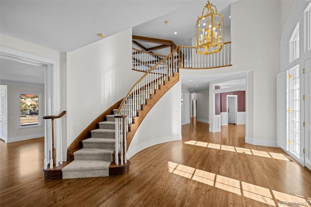 entryway with light hardwood / wood-style floors, a chandelier, and a high ceiling