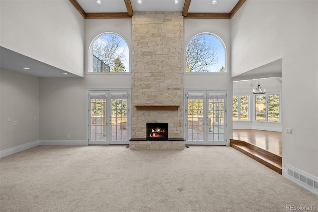 unfurnished living room with beamed ceiling, a wealth of natural light, a fireplace, and french doors