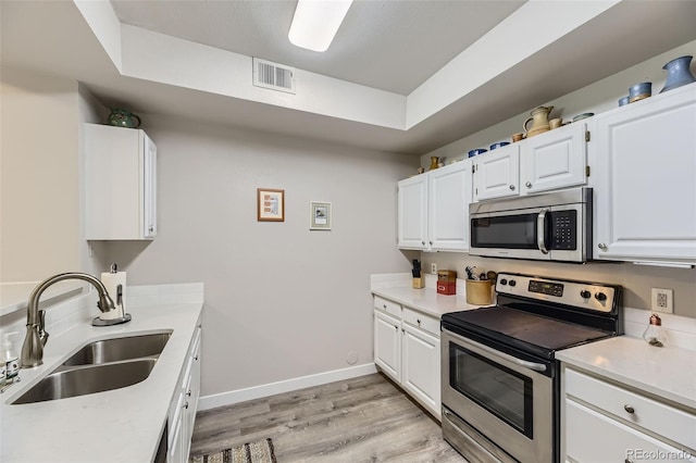 12818 Ironstone Way Unit 101, Parker, CO 80134 - kitchen featuring appliances with stainless steel finishes, a sink, light wood-style flooring, and white cabinetry