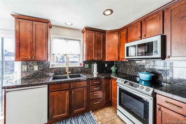 kitchen with appliances with stainless steel finishes, a textured ceiling, decorative backsplash, sink, and light tile patterned flooring