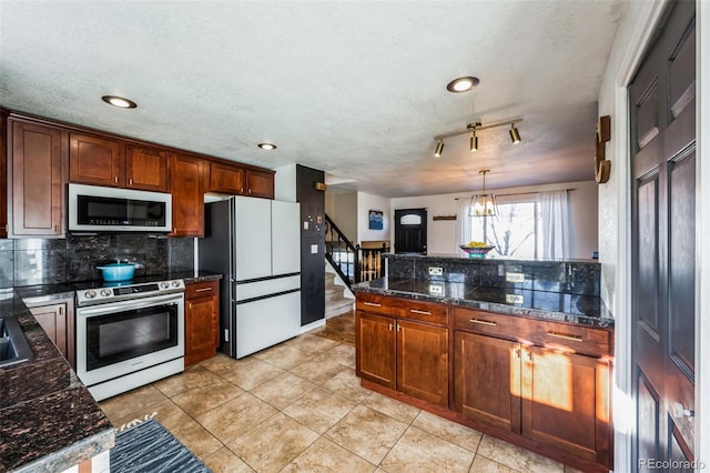 kitchen with white refrigerator, an inviting chandelier, tasteful backsplash, electric stove, and pendant lighting