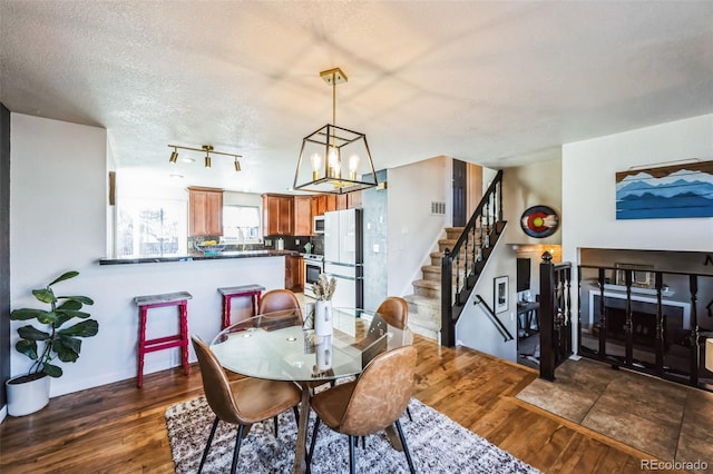 dining room with an inviting chandelier, a textured ceiling, and dark hardwood / wood-style flooring