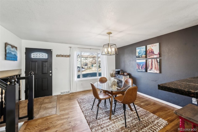 dining space with a textured ceiling, a chandelier, and hardwood / wood-style flooring