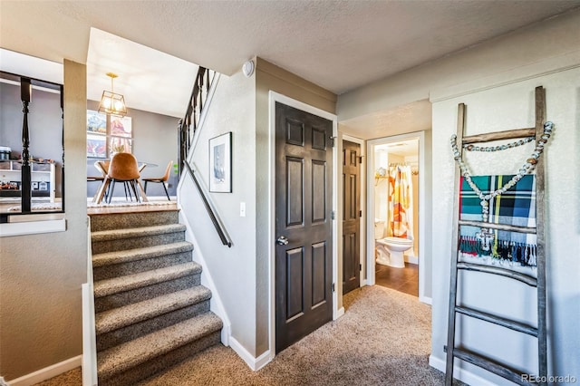 stairs with a textured ceiling and carpet