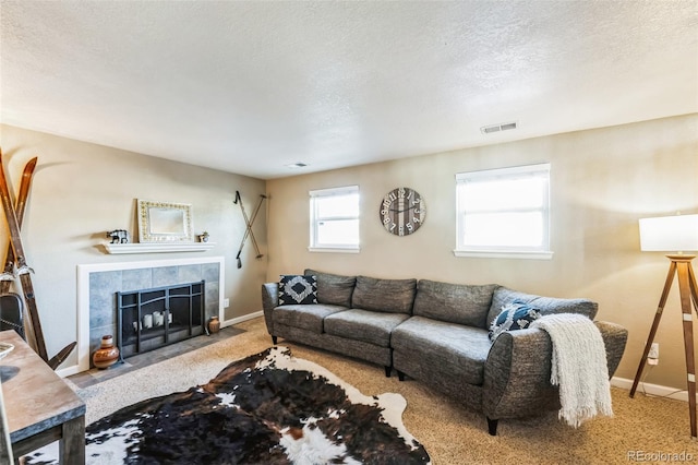 carpeted living room with a tiled fireplace and a textured ceiling