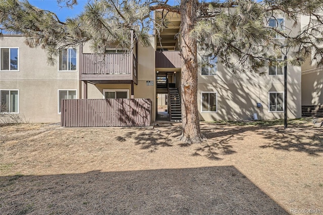 back of house with stairs and stucco siding