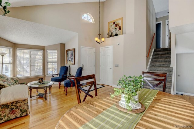 living room featuring high vaulted ceiling, a chandelier, hardwood / wood-style flooring, and plenty of natural light