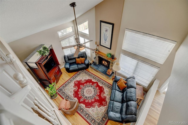 living room featuring a stone fireplace, hardwood / wood-style floors, and ceiling fan