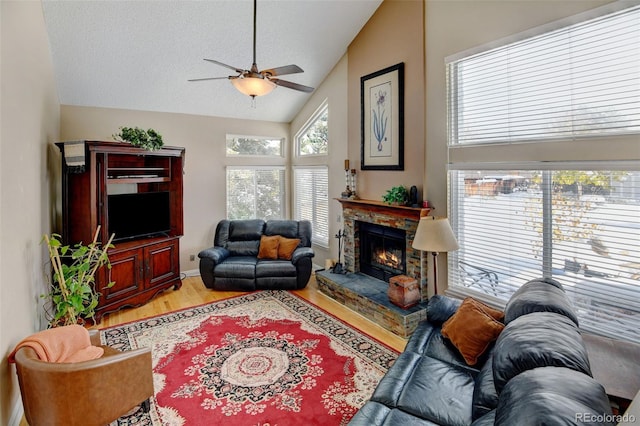 living room featuring a fireplace, light hardwood / wood-style floors, lofted ceiling, and ceiling fan