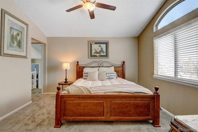 bedroom featuring ceiling fan, a textured ceiling, vaulted ceiling, and light colored carpet