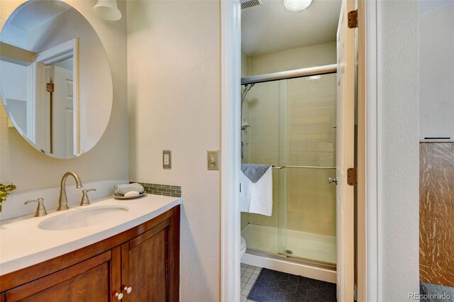 bathroom with tile patterned flooring, vanity, toilet, and a shower with door