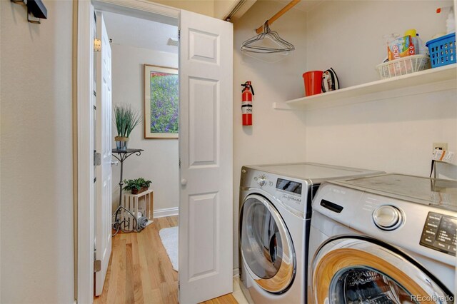 clothes washing area with light hardwood / wood-style flooring and washer and clothes dryer