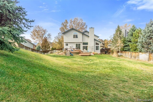 rear view of property featuring a deck and a lawn