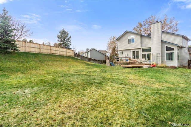 rear view of house with a lawn and a wooden deck