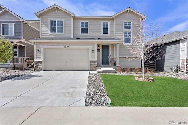 view of front of home featuring an attached garage, stone siding, driveway, and a front yard