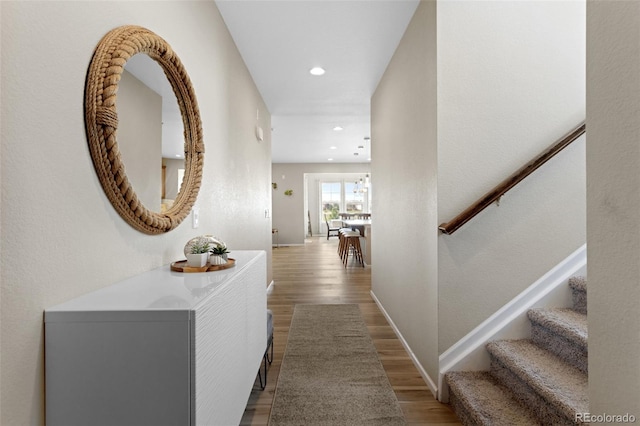 corridor with recessed lighting, baseboards, wood finished floors, and stairway