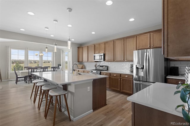 kitchen with tasteful backsplash, brown cabinets, a sink, a breakfast bar, and stainless steel appliances