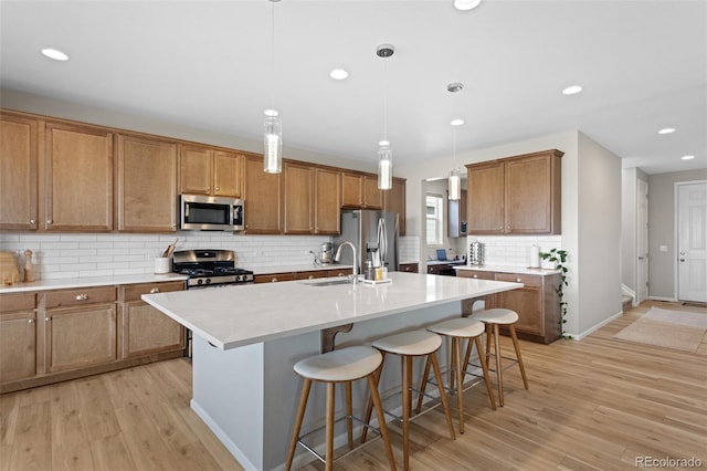 kitchen with appliances with stainless steel finishes, light wood finished floors, a breakfast bar area, recessed lighting, and decorative backsplash
