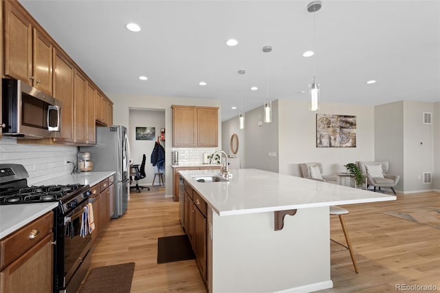 kitchen featuring open floor plan, a kitchen breakfast bar, tasteful backsplash, a sink, and stainless steel appliances