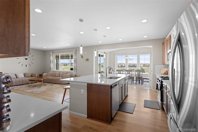 kitchen featuring a sink, light wood finished floors, a breakfast bar, stainless steel appliances, and an island with sink