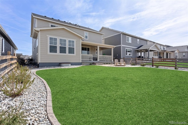 back of property featuring a yard, fence, and covered porch