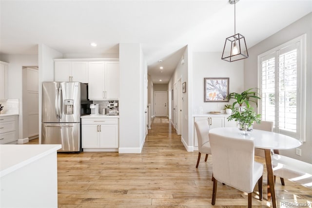 kitchen with light wood-type flooring, white cabinetry, backsplash, and stainless steel fridge with ice dispenser