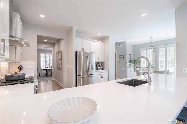 kitchen with tasteful backsplash, white cabinets, appliances with stainless steel finishes, light countertops, and a sink