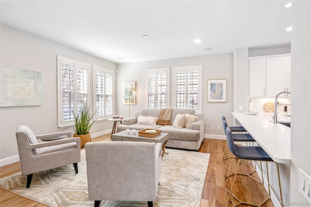 living room with recessed lighting, light wood-style flooring, and baseboards