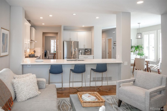 kitchen featuring stainless steel fridge, plenty of natural light, and a peninsula