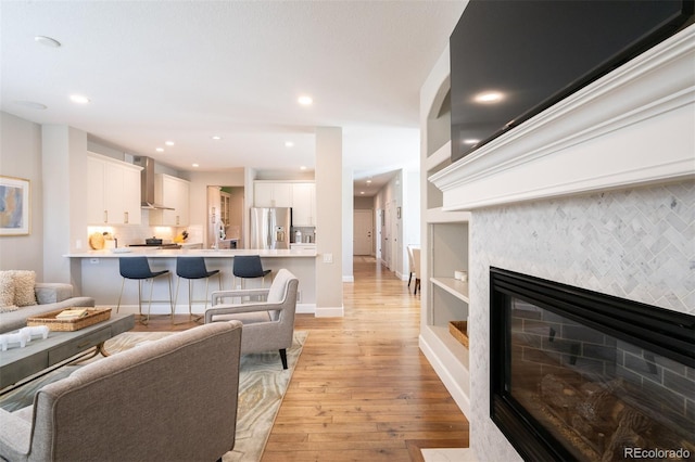 living room with light wood-style floors, recessed lighting, baseboards, and a glass covered fireplace